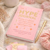 The Hype Journal displayed in a soft flatlay with flowers and candle on white background
