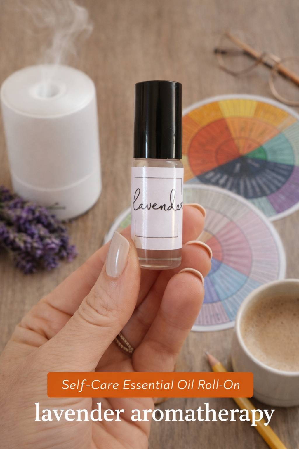 Hand holding a lavender essential oil roll-on with a diffuser, mug, and color wheel in the background.