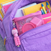 Purple backpack open to reveal Coping Skills Kids Kit stationery items including notebooks, pens, and a pink Lego-themed keychain.